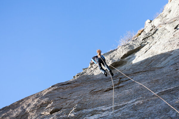 A rock climber abseiling off a climb