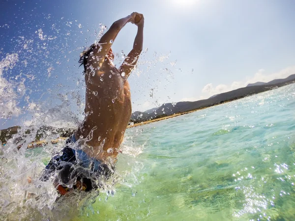 Caucásico joven saltando en el agua, jugando y divirtiéndose — Foto de Stock