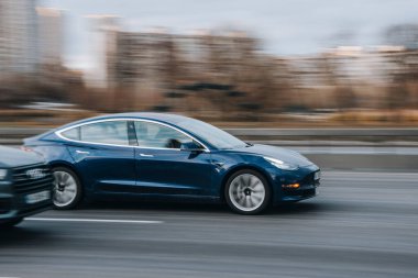 Ukrayna, Kyiv - 23 Kasım 2021: Mavi TESLA Model 3 aracı yolda ilerliyor. Yazı