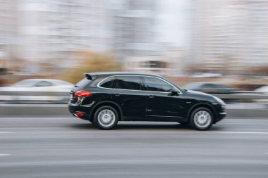 Ukrayna, Kyiv - 23 Kasım 2021: Siyah Porsche Cayenne arabası sokakta hareket ediyor. Yazı