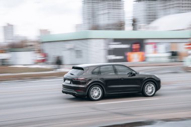 Ukrayna, Kyiv - 15 Ocak 2022: Siyah Porsche Cayenne arabası sokakta hareket ediyor. Yazı