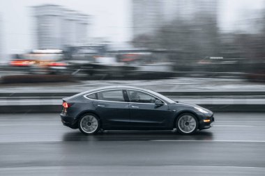 Ukrayna, Kyiv - 15 Ocak 2022: Gri TESLA Model 3 aracı sokakta hareket ediyor. Yazı