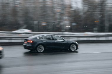 Ukrayna, Kyiv - 15 Ocak 2022: Gri TESLA Model 3 aracı sokakta hareket ediyor. Yazı