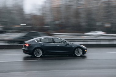 Ukrayna, Kyiv - 15 Ocak 2022: Gri TESLA Model 3 aracı sokakta hareket ediyor. Yazı