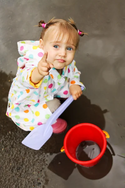 泥だらけの水たまりでかわいい女の子を再生します。 — ストック写真