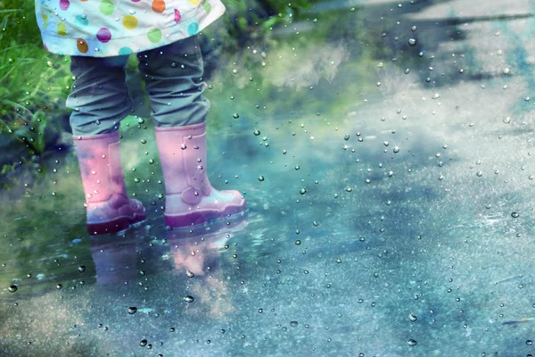 Cute little girl is playing in muddy puddles Royalty Free Stock Images