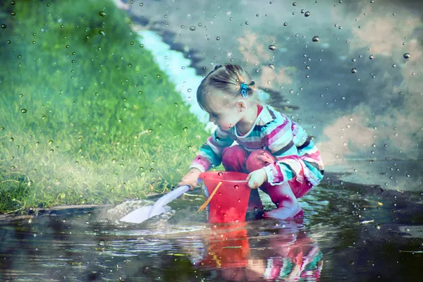 Cute little girl is playing in muddy puddles — Stock Photo, Image