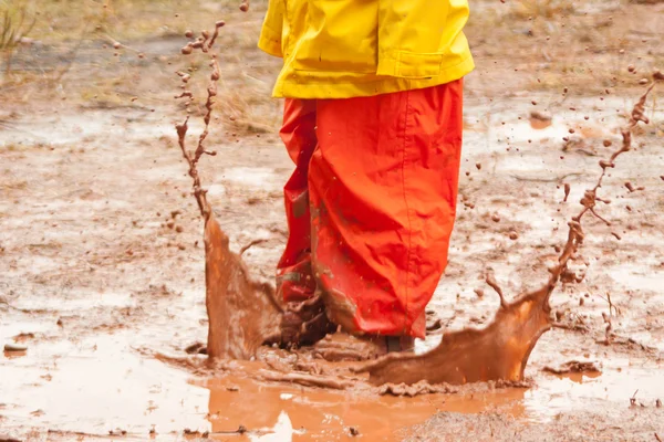 Liten flicka spelar i leriga pölar — Stockfoto