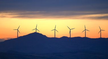 Wind turbines on sunset background clipart