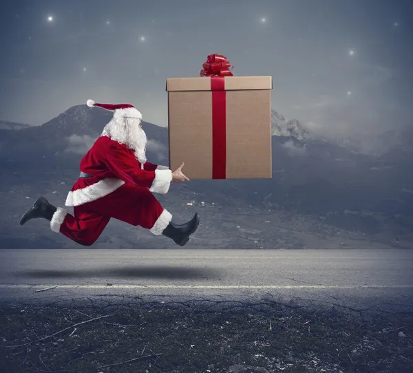 Running Santa Claus with big gift — Stock Photo, Image