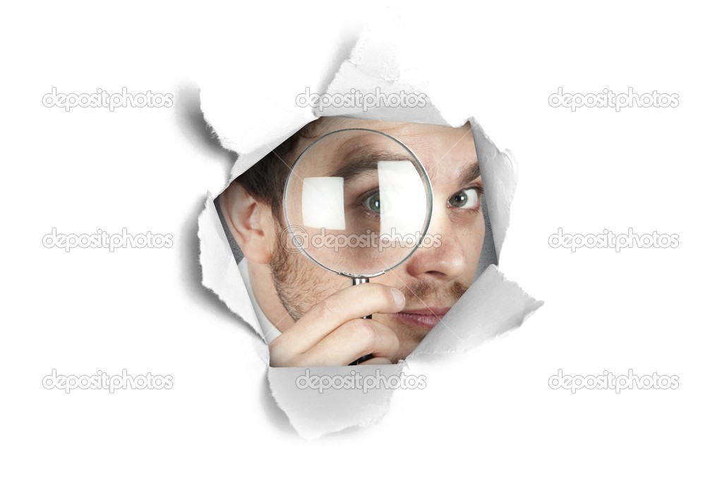 Businessman looking through a paper hole