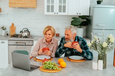 Çiftler kahvaltılarını evde yapar ve dizüstü bilgisayardan bir şeyler izlerler.