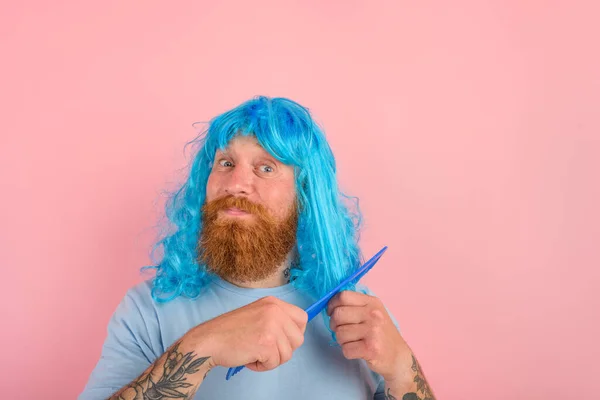 Счастливый мужчина с бородой и голубым перуком расчесывает волосы, как женщина — стоковое фото
