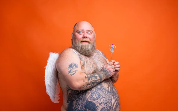 Hombre gordo asombrado con barba, tatuajes y alas actúa como un hada mágica — Foto de Stock