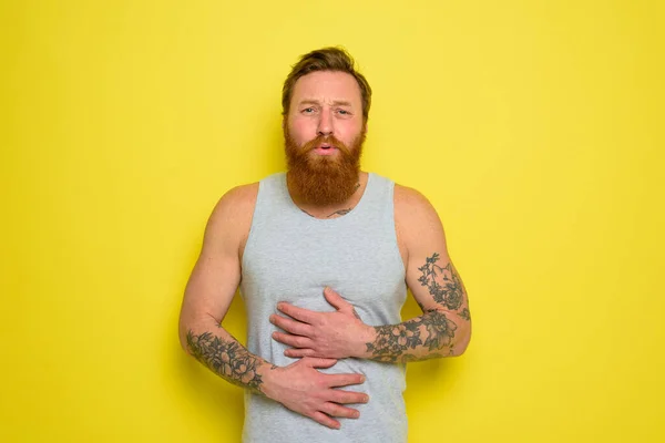 Suffering man with beard and tattoos has stomach ache — Stock Photo, Image