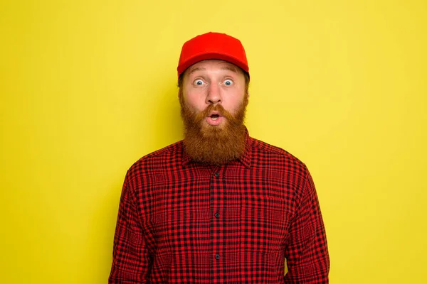 Uomo di consegna con cappello e barba ha un'espressione stupita — Foto Stock