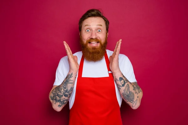 Szczęśliwy odizolowany szef kuchni z brodą i czerwonym fartuchem — Zdjęcie stockowe