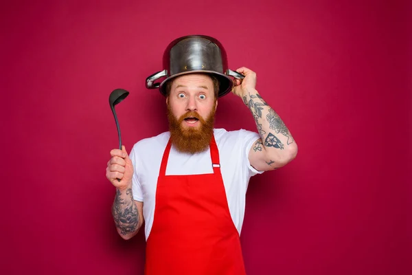 Stupito chef con barba e grembiule rosso gioca con pentola — Foto Stock