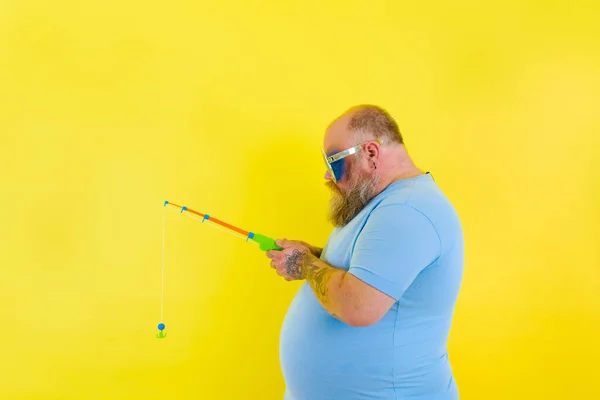 Fat man with beard and sunglasses is unhappy with the fishing rod — Stock Photo, Image