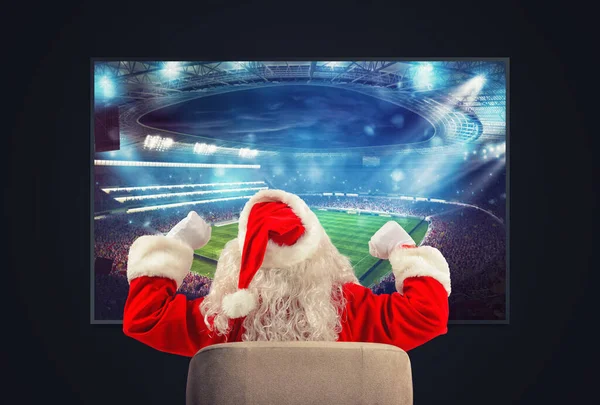 Santa Claus yang ceria, penggemar sepak bola, menonton pertandingan di televisi — Stok Foto