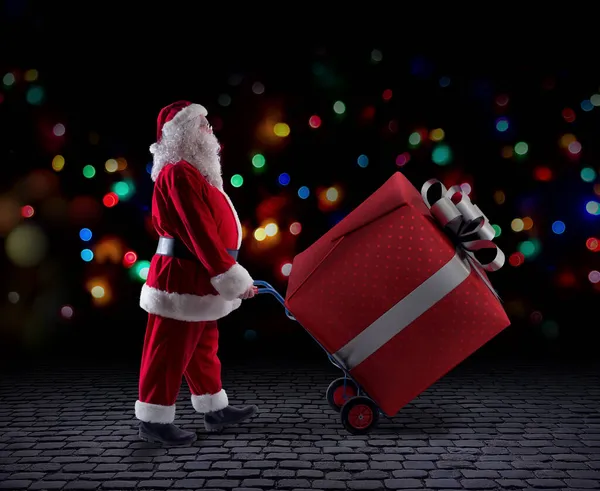 Santa claus delivers a big gift for Christmas — Stock Photo, Image