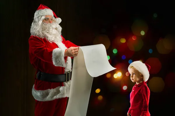 산타클로스는 일람표에서 아이에게 줄 선물을 찾는다 — 스톡 사진