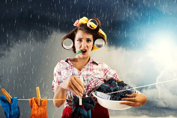 Unzufriedene Hausfrau hängt Kleider auf und es beginnt zu regnen — Stockfoto