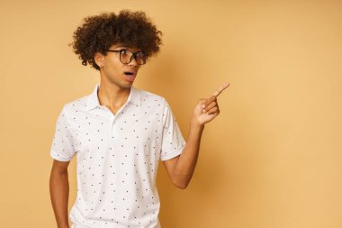 Gözlüklü hayret verici bir adam elle bir şey gösterir.