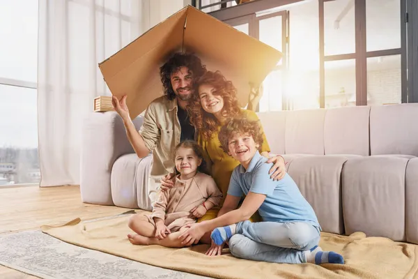 Gelukkig gezin spelen samen onder een kartonnen dak — Stockfoto