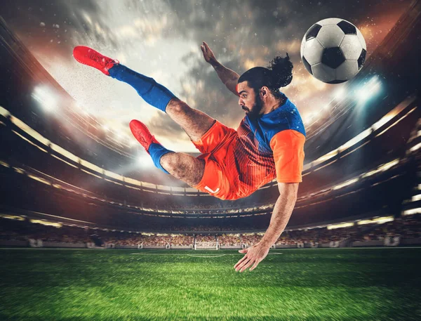 Turuncu ve mavi üniformalı bir futbolcu stadyumdaki topa akrobatik bir tekmeyle vuruyor. — Stok fotoğraf