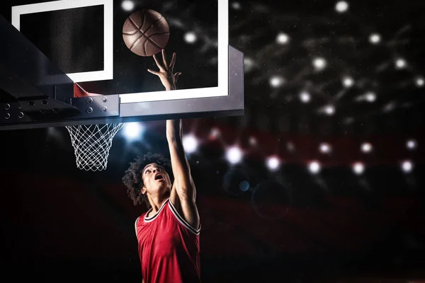 Jogador de basquete em uniforme vermelho pulando alto para fazer um slam dunk para a cesta — Fotografia de Stock