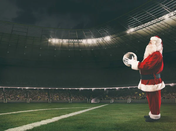 Kerstman met een voetbal in zijn handen in een voetbalstadion — Stockfoto