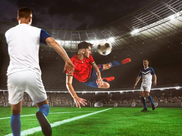 Футболист в красно-синей форме бьет по мячу выстрелом в голову в воздухе на стадионе — стоковое фото