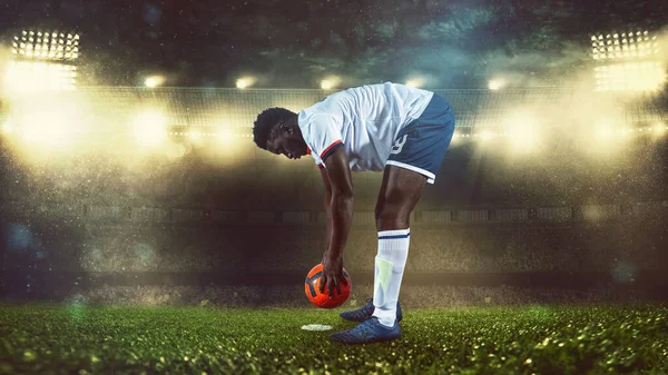 Escena de fútbol en el partido nocturno con el jugador en blanco y uniforme colocando la pelota para patear —  Fotos de Stock