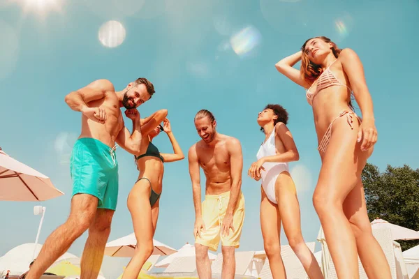 Grupo de amigos en traje de baño bailan música en una piscina — Foto de Stock