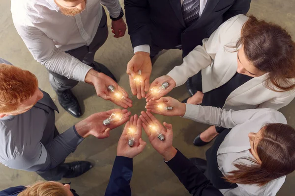 Trabajo en equipo y lluvia de ideas con hombres de negocios que comparten una idea con una lámpara — Foto de Stock