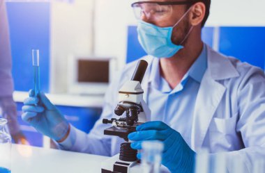 Laboratuvardaki doktor kodiv-9 örneklerini mikroskop altında analiz ediyor.