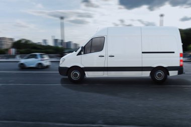 Beyaz minibüsü olan bir nakliye servisi yolda hızla ilerliyor.