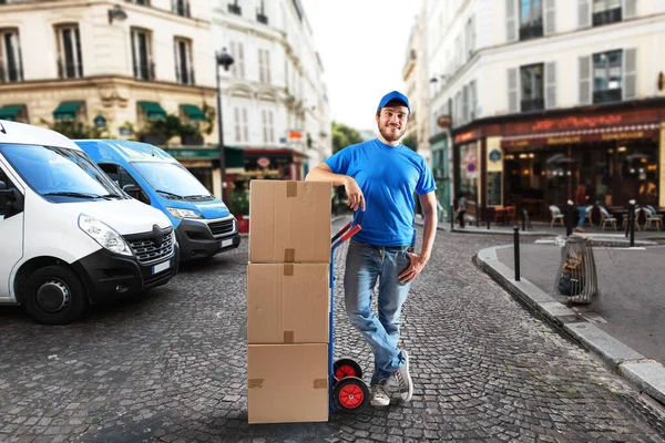 Homem com uniforme azul na frente das lojas para entrega e retirada das mercadorias — Fotografia de Stock