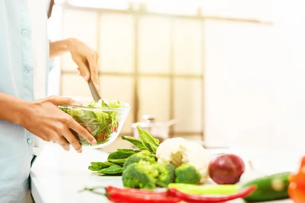 Mujer joven en la cocina casera prepara una ensalada genuina con verduras frescas — Foto de Stock