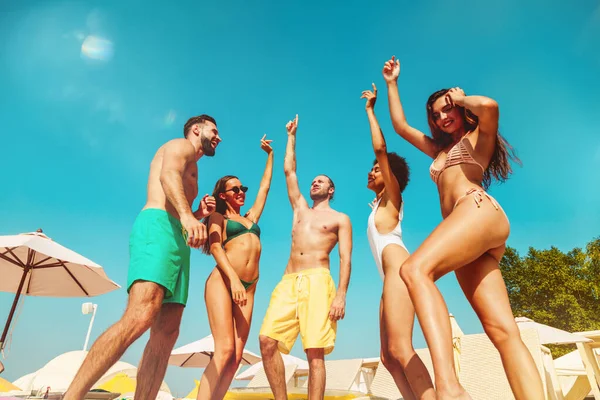 Gruppe von Freunden im Badeanzug tanzen Musik in einem Schwimmbad — Stockfoto