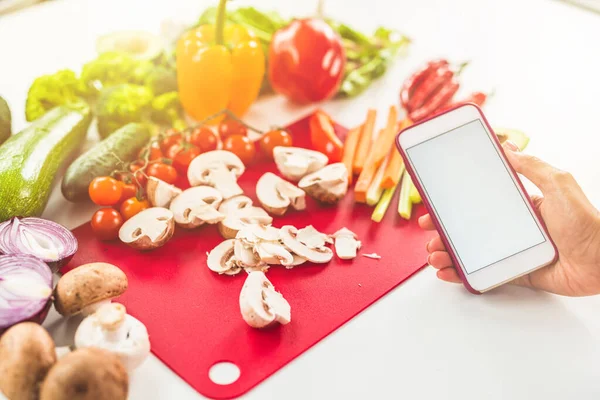 Cerca una ricetta su internet con il cellulare a base di ingredienti vegetali — Foto Stock