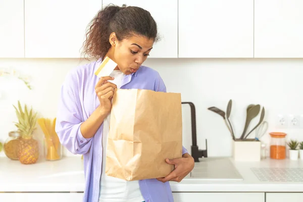 Mujer expresiva con una bolsa de compras ordenada en línea a través de pagos electrónicos entregados directamente en casa — Foto de Stock