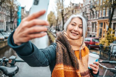 Kıdemli kadın Amsterdam 'da kahvaltı yapıyor ve selfie çekiyor.