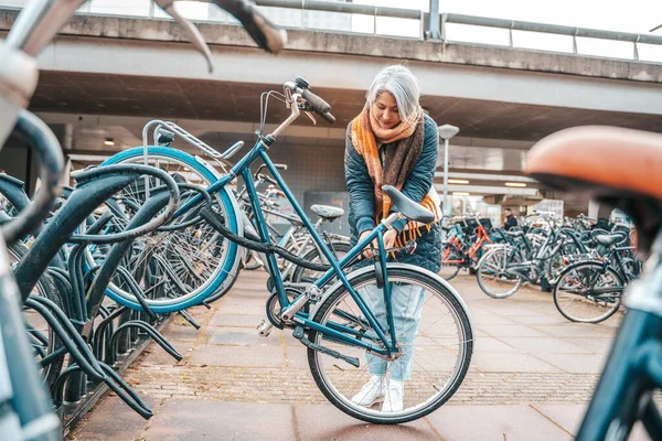 Senior woman gets the bike in a parking — Stockfoto