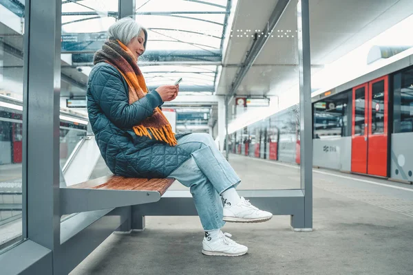 Senior woman buys the train ticket with the smartphone —  Fotos de Stock