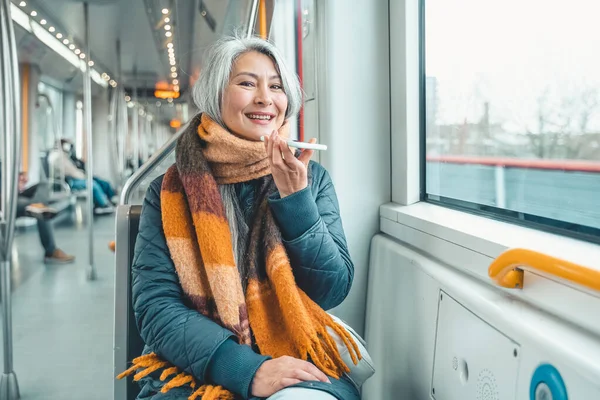Starsza kobieta wysłać wiadomość z telefonu komórkowego w pociągu — Zdjęcie stockowe