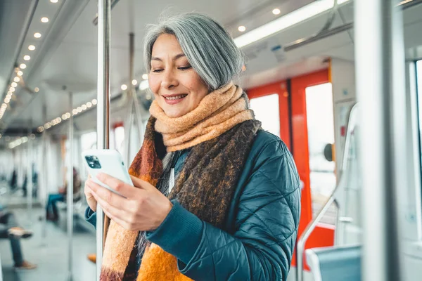 Старшая женщина отправляет сообщение с мобильного телефона в поезде — стоковое фото