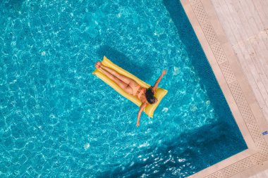 Yüzme havuzunda bronzlaşan mayo giymiş kız.