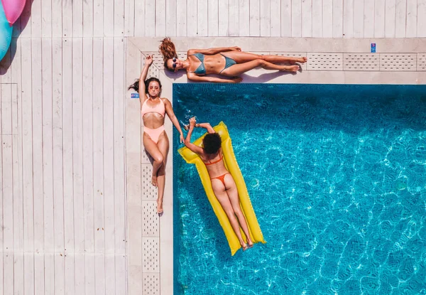 Amis en maillot de bain qui bronzent dans le transat dans une piscine — Photo